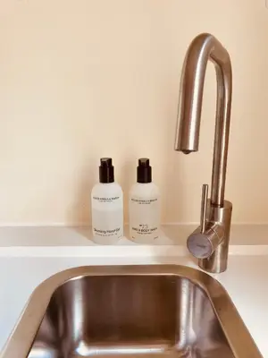 two bottles of soap sitting on a kitchen sink at Casita aan Zee 2 slaapkamers 2 badkamers 3 min van zee in Zandvoort