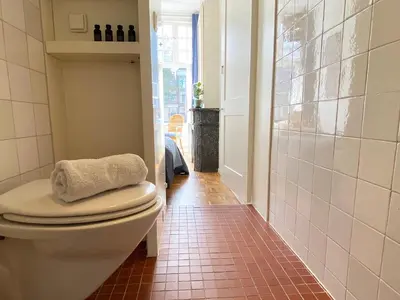 a bathroom with a toilet and a tile floor at Canal Hideaway in Amsterdam