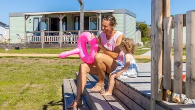 a man and a little girl sitting on a dock with a pink float at Molecaten Park Noordduinen in Katwijk