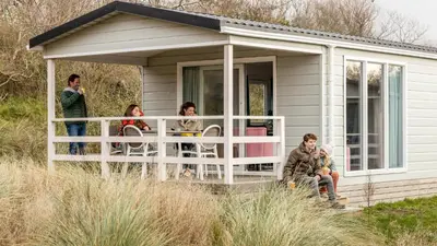 a group of people sitting on the porch of a caravan at Molecaten Park Noordduinen in Katwijk