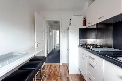 a kitchen with white cabinets and black counter tops at familie Zwinkels in Zandvoort