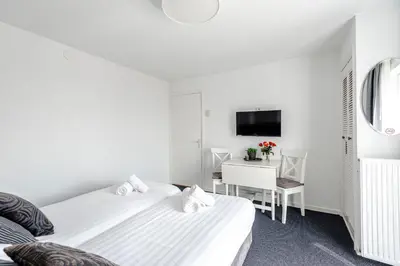 two beds in a room with a desk and a tv at familie Zwinkels in Zandvoort