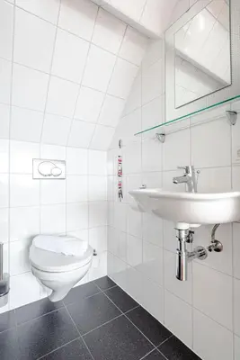 a white bathroom with a toilet and a sink at familie Zwinkels in Zandvoort