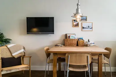 a dining room table with chairs and a tv on the wall at B&B Amsterdam Amstel Apartment in Amsterdam