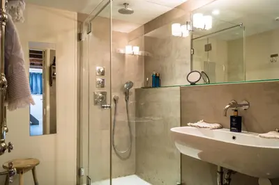 a bathroom with a shower and a sink and a glass shower door at B&B Amsterdam Amstel Apartment in Amsterdam