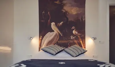 a painting of birds and a book on a bed at Boutique Hotel Bellevue in Blaricum