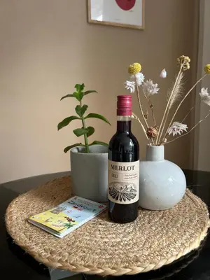 a bottle of wine and a book on a table at Appartement van der Zee in Zandvoort