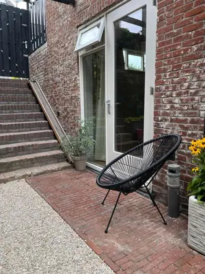 a black bench sitting in front of a brick house at Appartement van der Zee in Zandvoort