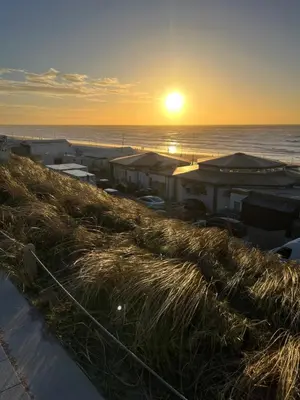 a sunset over the ocean with buildings on a beach at Appartement van der Zee in Zandvoort
