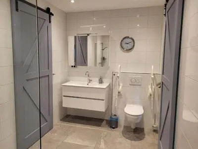 a bathroom with a sink and a toilet and a clock at B & B De Tocht in Berkhout
