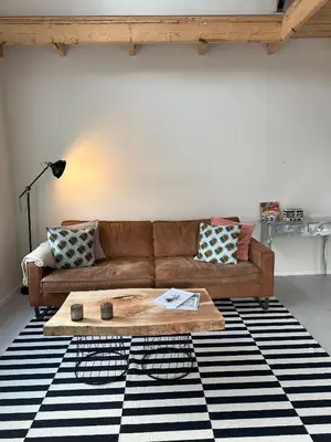 a living room with a brown couch and a table at trendy boutique appartement vlak bij Amsterdam in Rijnsaterwoude