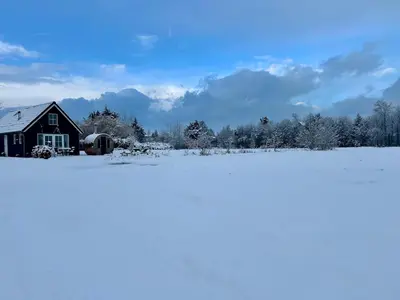 a barn in a snow covered field with trees at Stuga Kodawari in Voorhout
