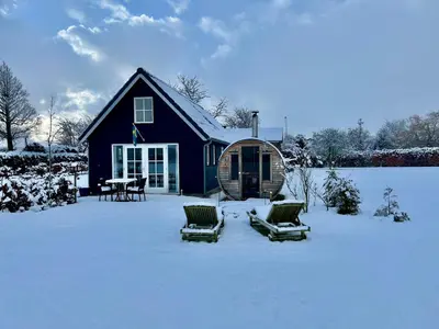 a house with two chairs and a table in the snow at Stuga Kodawari in Voorhout
