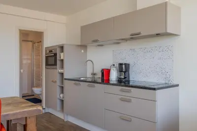 a kitchen with white cabinets and a counter top at De Schelp 85 in Zandvoort