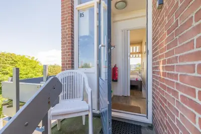 a porch with two white chairs and a door at De Schelp 85 in Zandvoort