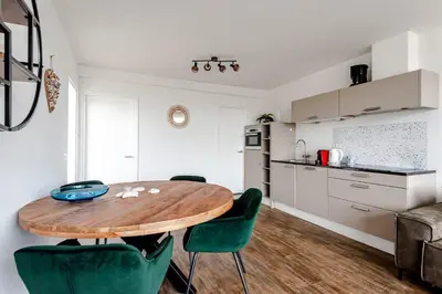 a kitchen and dining room with a wooden table and chairs at De Schelp 85 in Zandvoort