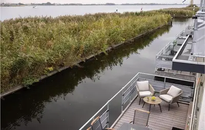 a boat with two chairs and a table on the deck at 2 Bedroom Stunning Ship In Aalsmeer in Aalsmeer