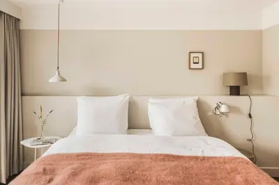 a bedroom with a white bed with a orange blanket at Boutique Hotel Weesp in Weesp