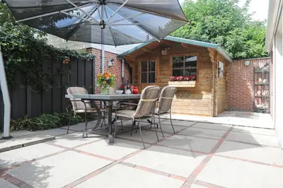 a patio with a table and chairs and an umbrella at Sunnybeachhouse aan het bos, tussen zee en meer. in Noordwijkerhout