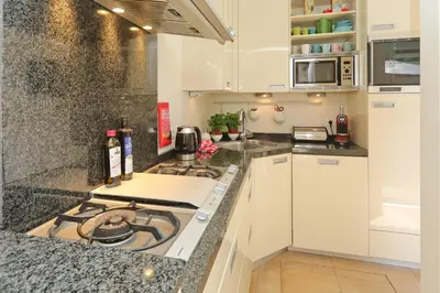 a kitchen with white cabinets and a stove top oven at Sunnybeachhouse aan het bos, tussen zee en meer. in Noordwijkerhout