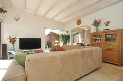 a living room with a couch and a tv at Sunnybeachhouse aan het bos, tussen zee en meer. in Noordwijkerhout