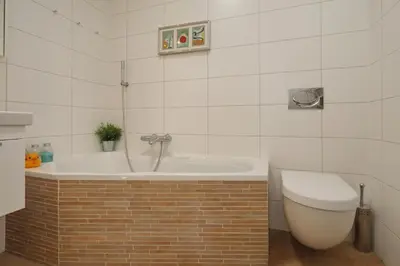 a bathroom with a bath tub and a toilet at Sunnybeachhouse aan het bos, tussen zee en meer. in Noordwijkerhout