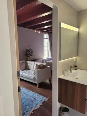 a bathroom with a sink and a living room with a couch at Het Waterhof in Leiden