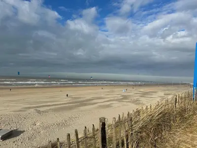 a beach with a fence and people on the sand at Studio34 Zandvoort free parking in Zandvoort