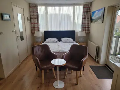 a bedroom with a bed with two chairs and a table at Pension Canberra in Bergen aan Zee
