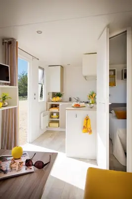 a kitchen with white cabinets and a living room at Vakantiepark Koningshof in Rijnsburg