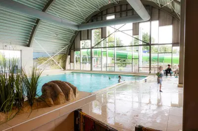 a swimming pool in a building with people in it at Vakantiepark Koningshof in Rijnsburg