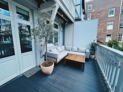 a porch with a couch and a table on a balcony at Spacious Designer Duplex next to Central Park in Amsterdam