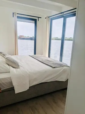 a bedroom with a large bed and a large window at 6 personen luxe houseboat Splendid Monnickendam nabij Amsterdam in Monnickendam