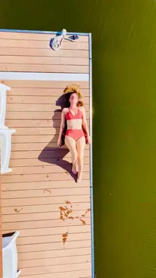 a woman in a bikini sitting on a wooden wall at 6 personen luxe houseboat Splendid Monnickendam nabij Amsterdam in Monnickendam