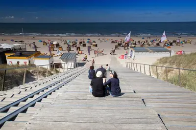 a group of people sitting on a pier at the beach at Vakantiewoning 't Juttershuis Egmond aan Zee in Egmond aan Zee