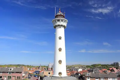 a white lighthouse on top of a city at Vakantiewoning 't Juttershuis Egmond aan Zee in Egmond aan Zee