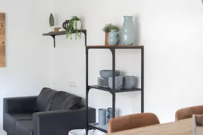 a living room with a black shelf with plates and vases at Vakantiewoning 't Juttershuis Egmond aan Zee in Egmond aan Zee