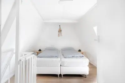 a white room with a bed in the attic at Vakantiewoning 't Juttershuis Egmond aan Zee in Egmond aan Zee