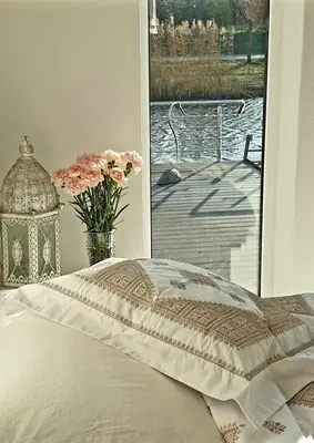 a bed with a vase of flowers next to a window at Amberdi Apartment Amsterdam Schiphol Airport in Hoofddorp