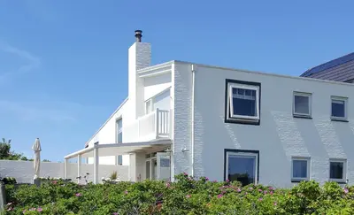 a white house with a chimney on the side of it at appartement Ideaal in Bergen aan Zee