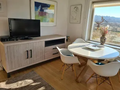 a living room with a tv and a table and chairs at appartement Ideaal in Bergen aan Zee