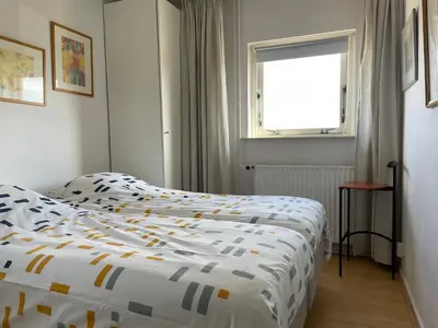 a bedroom with a bed with a comforter and a window at appartement Ideaal in Bergen aan Zee