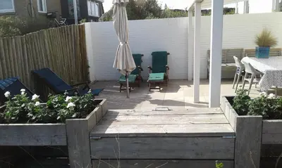 a patio with a table and an umbrella and chairs at appartement Ideaal in Bergen aan Zee