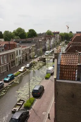 a city with cars parked on a street and a river at Canal House in Historic City Center Gouda in Gouda