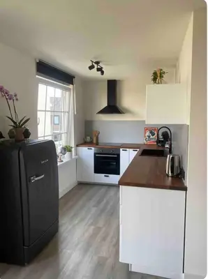 a kitchen with a black refrigerator and white cabinets at Studio Romantic in Zandvoort
