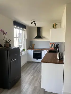 a kitchen with a black refrigerator and white cabinets at Studio Romantic in Zandvoort