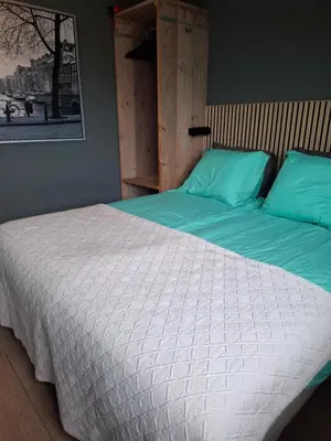 a bedroom with a bed with green and white sheets at B&B Zee-en-Zo Noordwijk in Noordwijk