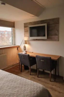 a bedroom with a desk and a television on a wall at B&B Zee-en-Zo Noordwijk in Noordwijk