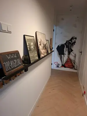 a hallway with a shelf with books and pictures on a wall at B&B Zee-en-Zo Noordwijk in Noordwijk