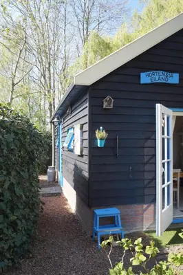 a black house with a blue stool in front of it at Hortensia Eiland in Zegveld